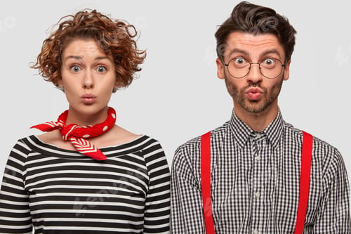 Preview: Photo Of Fashionable Woman And Man Pout Lips, Gaze With Surprised Intrigued Expressions, Stand