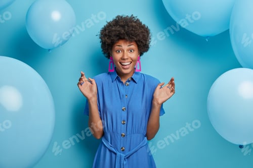 Visualização: Mulher afro-americana alegre feliz em encontrar amigos na festa, fica de pé com as mãos levantadas e sorri
