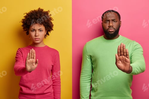 Preview: Serious Looking Dark Skinned Woman And Man Extend Palms At Camera, Make Stop Warning Gesture