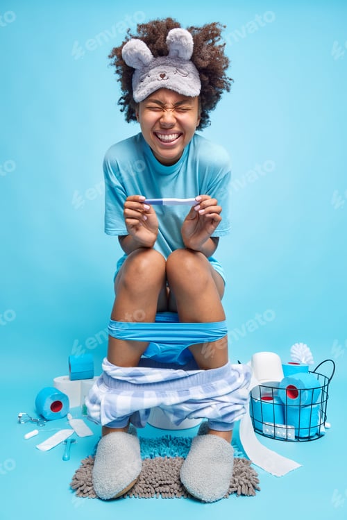 Preview: Positive Curly Haired Young Woman Holds Pregnancy Test Happy To Finds Out She Is Pregnant Sits On