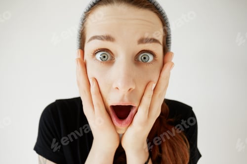 Preview: Stunned Woman Holding Hands On Her Cheeks Shocked With Unexpected News. Isolated Headshot Of