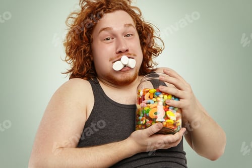 Preview: Hungry Funny Redhead Overweight Caucasian Male Looking At Camera With Mouth Full With Marshmallow