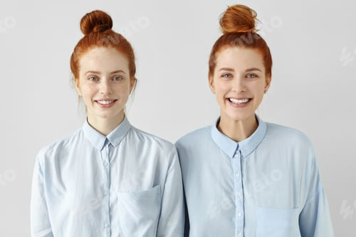 Preview: Two Young Redhead Caucasian Females Looking Alike Wearing Same Formal Light-Blue Shirts, Looking At