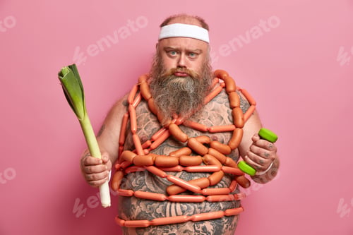 Preview: Unhappy Obese Fatso Man Wears White Sports Headband, Holds Dumbbell And Green Leek, Has Tattooed