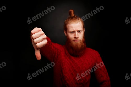 Preview: Portrait Of Bearded Man In A Red Knitted Sweater Looking At Camera And Showing His Thumbs Down
