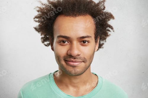Preview: Headshot Of Stylish Hipster Guy With Bushy Hairstyle, Stubble, Shining Eyes, Poses In White Studio