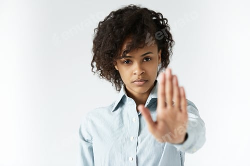 Preview: African Woman With Curly Hair Wearing Striped Shirt, Showing Stop Gesture With Her Left Hand