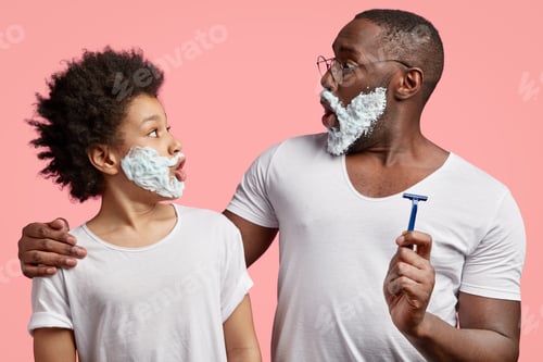 Preview: Side View Of Black Father And Son Stare At Each Other, Have Shaving Gel On Faces, Have Surprised