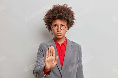 Preview: Serious Displeased Businesswoman In Formal Clothes Keeps Palm Forward Camera In Restriction Gesture