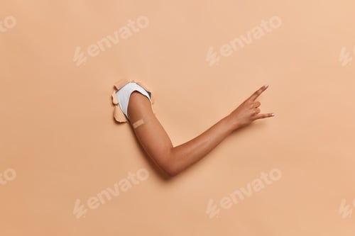Preview: Vaccination And Immunization Concept. Human Arm Breaking Through Brown Paper Background Gesturing