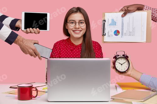 Preview: Horizontal Shot Of Smiling Beautiful Woman In Red Shirt, Sits In Front Of Opened Laptop Computer