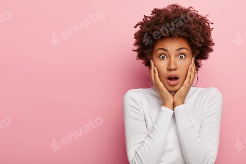 Preview: Headshot Of Stupefied Emotional Dark Skinned Woman Gazes At Camera With Shock, Keeps Jaw Dropped