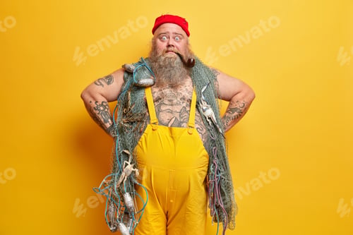 Preview: Photo Of Surprised Bearded Guy With Thick Long Beard, Keeps Hands On Hips, Wears Yellow Overalls