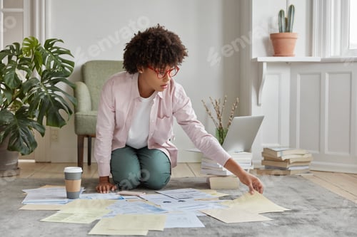 Preview: Indoor Shot Of Busy Young Woman Dressed In Casual Clothes, Sits On Floor With Paper Documents