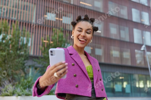 Preview: Fashionable Young Woman With Bun Hairstyle Winks Eye Poses For Selfie At Smartphone Camera Wears