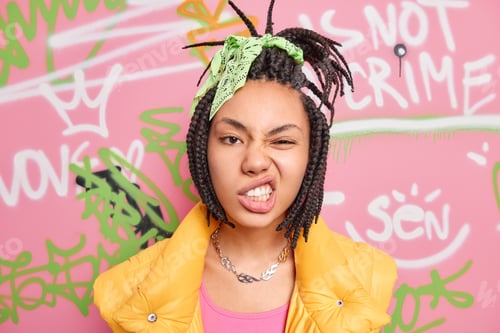 Preview: Teenage Lifestyle Concept. Cheeky Hipster Girl With Combed Dreadlocks Clenches Teeth Smirks Face