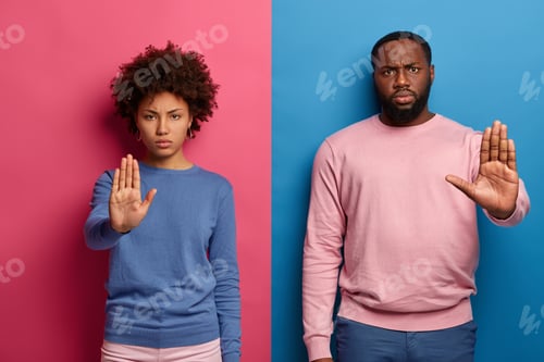 Preview: Prohibition Symbol. Serious Displeased Black Man And Woman Make Stop Gesture With Palms, Look In