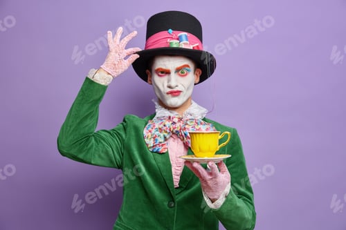Preview: Serious Mysterious Male Character From Wonderland Frowns Face Keeps Hand On Hat Drinks Tea On Party