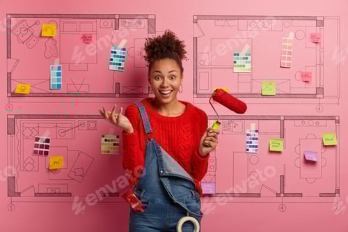 Preview: Positive Dark Haired Woman With Curly Hair, Holds Paint Roller, Smiles Gladfully, Wears Red Jumper