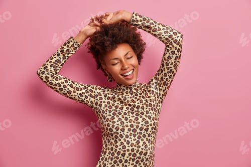 Vista previa: Happy Dark Skinned Woman Shakes Body, Raises Hands And Dances Carefree, Wears Leopard Jumper