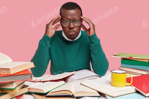Preview: Photo Of Upset Black Young Male Worker Has Headache, Works Hard, Reads Literature, Suffers From