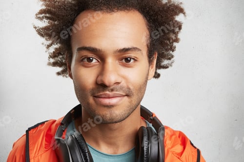 Preview: Close Up Portrait Of Attractive Man With Afro Hairstyle, Stubble, Wears Orange Anorak, Has Modern