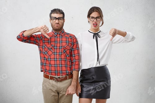 Preview: Discontent Woman And Man Keep Thumbs Down, Disapprove Something, Frown Faces, Isolated Over White