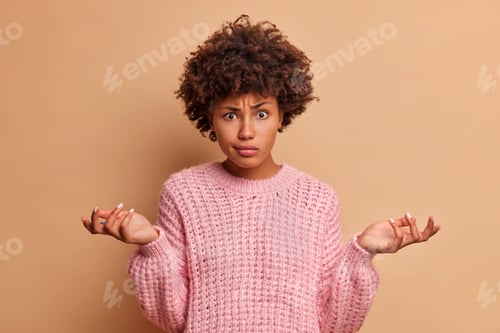 Preview: Confused Dark Skinned Young Woman With Afro Haircut Spreads Palms And Faces Dilemma Has Difficult