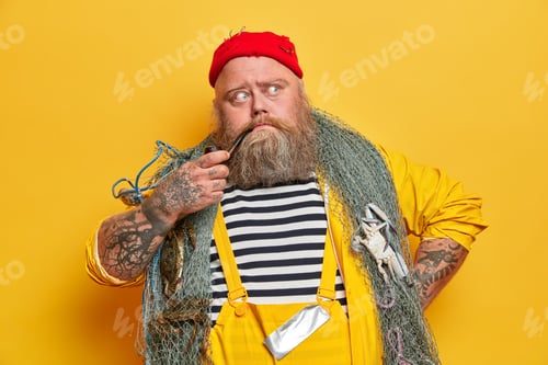 Preview: Old Experienced Bearded Sailor Thinks About Next Day At Sea, Poses With Fishing Gear, Smokes Pipe