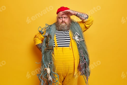Preview: Bearded Serious Fisher Keeps Hand On Forehead And Looks Into Distance, Poses With Fishing Net Over
