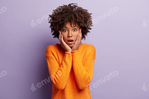 Preview: Terrific Dark Skinned Woman Touches Cheeks, Opens Eyes With Surprirsement, Keeps Jaw Dropped, Has