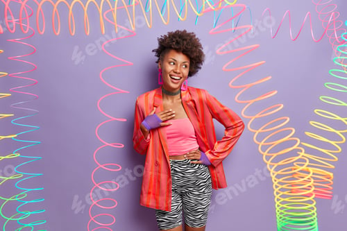 Preview: Positive Dark Skinned Woman Laughs Happily, Keeps Hand On Hip, Dressed In Fashionable Outfit, Poses
