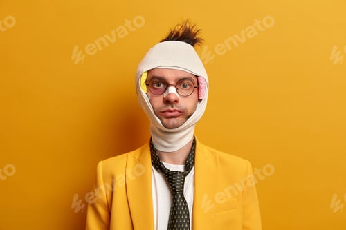 Preview: Serious Man With Swollen Cheeks And Shiner Under Eye, Bandage Over Head, Looks Directly At Camera