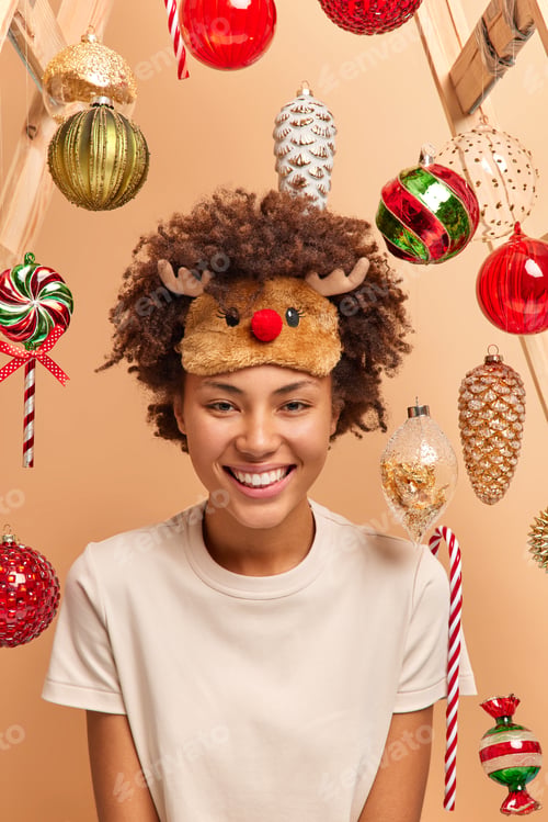 Preview: Positive Dark Skinned Woman Wears Deer Sleep Mask And Casual T Shirt Smiles Broadly Waits For