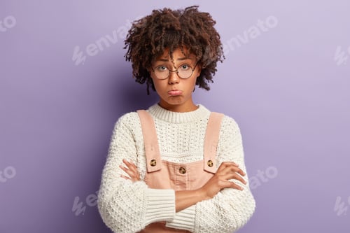Vista previa: Gloomy Dissatisfied Dark Skinned Woman With Afro Hairstyle, Keeps Arms Folded, Looks With Offensive