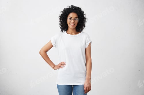 Preview: Stylish Young Dark-Skinned Female With Curly Hair Looking At Camera And Smiling Cutely, Posing With