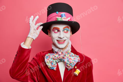 Preview: Funny Friendly Positive Hatter Keeps Hand On Hat Looks Away With Smile Dressed In Costume With Big