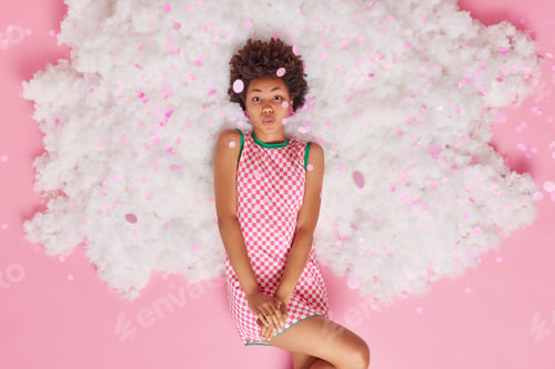 Preview: Romantic Curly Haired Young Woman Keeps Lips Folded Wants To Kiss You Dressed In Checkered Dress