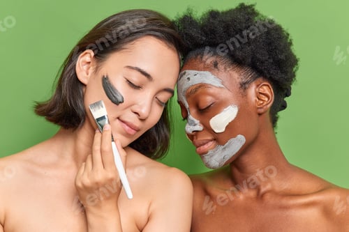 Preview: Portrait Of Two Diverse Women Stand Shirtless Next To Each Other Apply Clay Beauty Peeling Mask