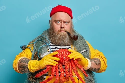 Preview: Strict Serious Man With Thick Beard, Holds Big Red Crab, Smokes Tobacco Pipe, Enjoys Sailing And
