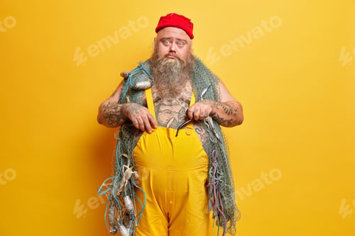 Preview: Sad Unhappy Bearded Skilled Man Sailor Poses With Fishing Gears, Holds Smoking Tobacco Pipe In