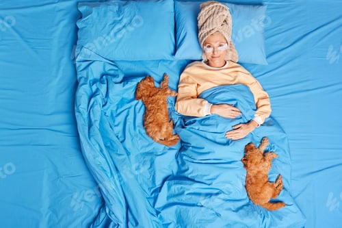 Preview: Top View Of Senior European Woman Wears Pajama Wrapped Towel On Head Eye Patches To Reduce Wrinkles