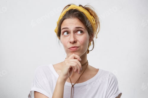 Preview: Pensive Beautiful Woman Wearing Yellow Headband And White T-Shirt Looking Aside, Thinking About