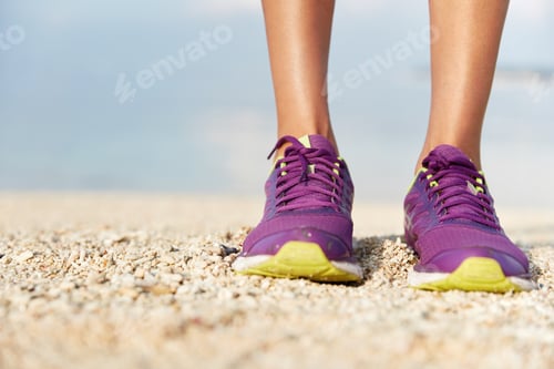 Preview: Female`S Runner Legs In Sport Shoes Stands On Beach Covered With Shells, Does Jogging Exercise