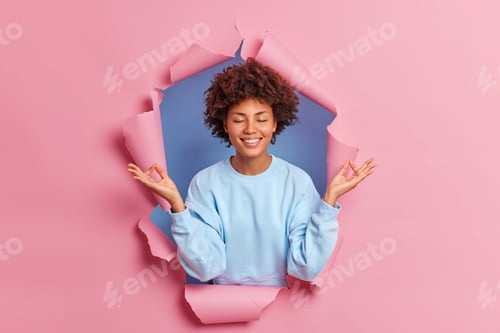 Preview: Positive Dark Skinned Woman Shows Zen Or Okay Sign As If Meditating Poses With Closed Eyes Smiles