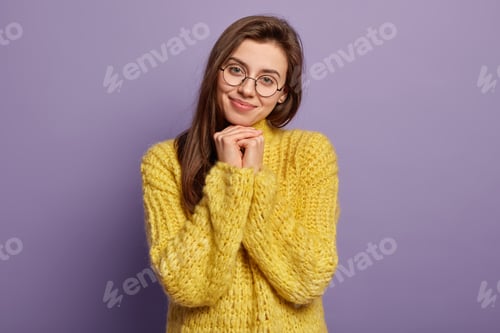 Preview: Pretty Young Woman With Healthy Skin, Keeps Hands Together Under Chin, Has Appealing Look, Dressed