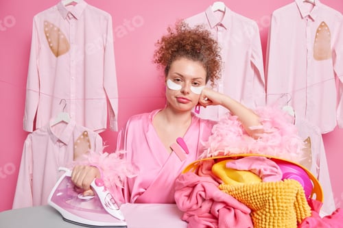 Preview: Housework And Household Concept. Sad Tired Curly Woman Dressed In Dressing Gown Applies Collagen