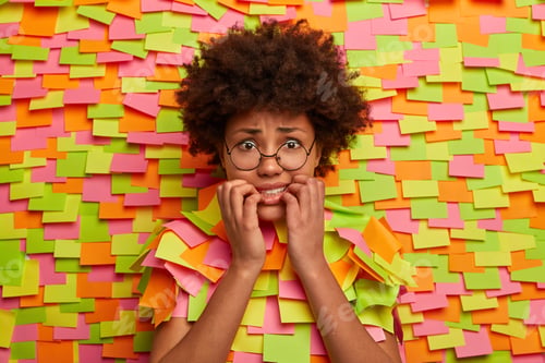 Preview: Portrait Of Nervous Afro American Woman Bites Finger Nails, Looks Anxious And Fearful At Camera