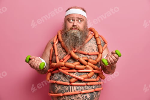 Preview: Fat Bearded Man Frustrated Because Of Diet Failure Poses With Two Dumbbells Sausages Around Body