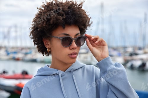 Preview: Curly Haired Young African American Woman Walks In Sea Port During Leisure Time Wears Sunglasses